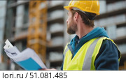 Construction manager reviews project plans on site during urban development in a bustling city environment. Стоковое AI-видео, аниматор Сергей Толмачёв / Фотобанк Лори