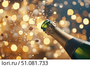 An energetic champagne bottle bursting open sends its cork and bubbles skyward. The scene captures lively festivity and sparkling celebration with effervescent joy and grandeur. Стоковое AI-изображение, AI-художник Nart / Фотобанк Лори