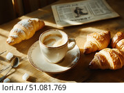 A top-down view of a classic French breakfast features buttery croissants and pain au chocolat. The rustic ceramic cup and cafÃ© au lait add warmth and charm to this timeless scene. Стоковое AI-изображение, AI-художник Nart / Фотобанк Лори