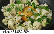 A person garnishes delicious cauliflower cut into pieces and fried in a pan with red cherry tomatoes and egg in a ring of orange bell pepper. Keto diet, low carb. Стоковое видео, видеограф Мария Зубарева / Фотобанк Лори