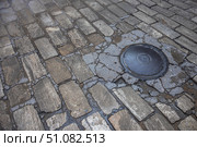 Cast-iron manhole on an old paved road. The road is paved with paving stones. A gray stone is laid on the road in an ancient city. A communication well in an ancient city. Стоковое фото, фотограф Эдуард Белкин / Фотобанк Лори