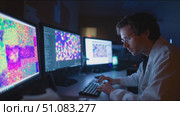 Scientist analyzing colorful data on multiple screens in a dark laboratory setting late at night. Стоковое AI-видео, аниматор Сергей Толмачёв / Фотобанк Лори