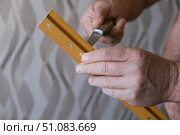 A male repairman drills a hole in the baseboard with a knife. Room renovation..... Стоковое фото, фотограф lyudmila Soloveva / Фотобанк Лори