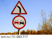 Two road signs warning no overtaking and turning right against a blue sky. Стоковое фото, фотограф lyudmila Soloveva / Фотобанк Лори