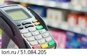 A close-up of a payment terminal in a retail store. The terminal features a keypad with colorful buttons. Shelves with products are blurred in the background. Стоковое AI-видео, аниматор Nart / Фотобанк Лори