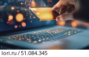 A hand holding a credit card above a laptop keyboard. The scene illustrates online shopping and digital transactions with glowing lights in the background. Стоковое AI-видео, аниматор Nart / Фотобанк Лори
