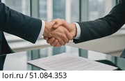 Two businessmen shaking hands over a contract on a glass table. The setting is a modern office with large windows and a city view. Стоковое AI-видео, аниматор Nart / Фотобанк Лори