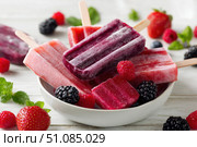 Berry juice popsicles in a plate on a white wooden table with fresh berries. Bright Ice pops with mint leaves and raspberries. Gut-health red pink berry popsicles. Inviting summer scene. Frozen treats. Стоковое AI-изображение, AI-художник Марина Демидюк / Фотобанк Лори