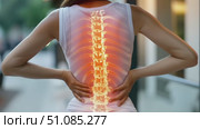 A young Asian woman with long black hair holds her lower back, showing a glowing spine illustration. The scene emphasizes health and wellness concepts. Стоковое AI-видео, аниматор Nart / Фотобанк Лори