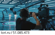 A male camera operator captures a female presenter in a futuristic studio. The setting features blue neon lights and advanced technology. Стоковое AI-видео, аниматор Nart / Фотобанк Лори