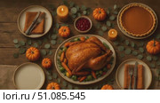 A beautifully arranged Thanksgiving dinner featuring a roasted turkey surrounded by pumpkins, candles, and side dishes on a rustic wooden table. Стоковое AI-видео, аниматор Nart / Фотобанк Лори