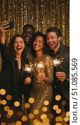 A diverse group of four young adults celebrate a corporate New Year party. They hold sparklers and toast with drinks in a festive office setting. Стоковое AI-видео, аниматор Nart / Фотобанк Лори