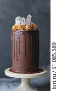 A Halloween-themed chocolate cake with orange frosting and ghost decorations. The cake features a glossy chocolate drip and is displayed on a white pedestal. Стоковое AI-видео, аниматор Nart / Фотобанк Лори