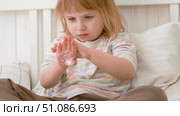 Baby girl finger applying moisturizing cream on her hand in white bedroom. Child puts lotion on hands. Skin care. Clean smooth body skin. Skincare, wellness, hygiene. Soft natural light, low contrast. Стоковое видео, видеограф Марина Демидюк / Фотобанк Лори