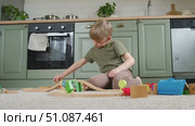 Cute little blonde child boy sitting on the floor playing with wooden toy train. Toddler kid plays railway. Made of natural materials. Birthday gift. Preschool employment. Brain, coordination exercise. Стоковое видео, видеограф Марина Демидюк / Фотобанк Лори