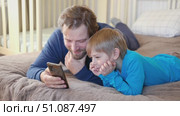 Father and son little boy laughing and using phone. They watching funny videos together, playing games on smartphone. Concept technology, smartphone addicted. Fun weekend activity. Modern fatherhood. Стоковое видео, видеограф Марина Демидюк / Фотобанк Лори