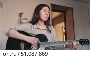 Woman Practicing Guitar in Cozy Room at Home. Strumming black acoustic guitar. Female learning to play music. Person hand on a guitar neck. Guitarist working on melody, performance, practice indoors. Стоковое видео, видеограф Марина Демидюк / Фотобанк Лори