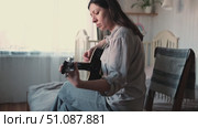 Woman Practicing Guitar in Cozy Room at Home. Strumming black acoustic guitar. Female learning to play music. Person hand on a guitar neck. Guitarist working on melody, performance, practice indoors. Стоковое видео, видеограф Марина Демидюк / Фотобанк Лори