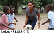 Children play football with a teacher in an African school, in the backyard. Black African children from disadvantaged families study in school, read books, receive primary education, volunteer service. Стоковое AI-изображение, AI-художник ALLA YURTAYEVA / Фотобанк Лори