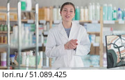 Professional young female pharmacist with arms crossed standing at pharmacy counter showing calm readiness to help customers choose right health products. Стоковое видео, видеограф Яков Филимонов / Фотобанк Лори