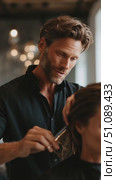 Hair stylist performs a precision haircut on a client in a modern salon setting with soft lighting. Стоковое AI-видео, аниматор Сергей Толмачёв / Фотобанк Лори