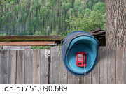 Vintage phone booth attached to wooden fence surrounded by lush greenery in a rural area during daylight hours. A payphone on a wooden fence in a Russian village. Lack of cellular communication. Стоковое фото, фотограф Владимир Разгуляев / Фотобанк Лори
