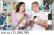 Positive young couple looking through barcode of liquid hand soap using smartphone while shopping. Стоковое видео, видеограф Яков Филимонов / Фотобанк Лори