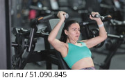 Athletic motivated woman using shoulder press machine in modern gym, focused on strength training and upper body fitness development. Стоковое видео, видеограф Яков Филимонов / Фотобанк Лори