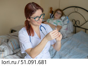 Call a doctor at home. The nurse gives an intramuscular injection to an elderly patient. A pensioner is sick and lies in bed. Стоковое фото, фотограф Михаил Решетников / Фотобанк Лори