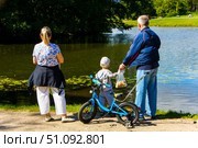 A family of three is standing by a body of water. Russia. Moscow. 17.08.25. Редакционное фото, фотограф Ярославский Максим / Фотобанк Лори