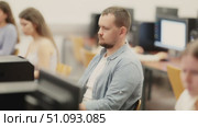 Side view on concentrated male student sitting at library desk with pc, preparing for exam in computer class. Стоковое видео, видеограф Яков Филимонов / Фотобанк Лори