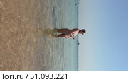 A 50-year-old European woman in a swimsuit walks along the beach in Doha, Qatar. Стоковое видео, видеограф IRYNA ZAKHARANKA / Фотобанк Лори