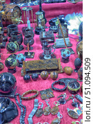 A vibrant display of various stone and mineral souvenirs and gifts laid out on a bright pink fabric. The items include desktop globes, office accessories, clocks, bracelets, rings, keychains, pen holders, and decorative spheres — all crafted from polished semi-precious stones with intricate textures. The setting evokes the feeling of a craft market or artisan fair. Стоковое фото, фотограф Анна Кривицкая / Фотобанк Лори