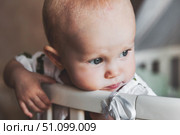 Daydreaming Baby Leans on the Railing of Their Crib in the Nursery. Стоковое фото, фотограф Aleksandr Golubev / Фотобанк Лори