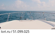 Front deck view from luxury motor yacht sailing on calm blue sea towards distant coastline with mountains under sunny sky, showcasing chrome railings and peaceful maritime travel scene. Стоковое видео, видеограф Сергей Тимофеев / Фотобанк Лори