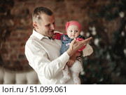 Holding Newborn Daughter Tenderly, Dad Shares Joyful Moment in the Living Room. Стоковое фото, фотограф Aleksandr Golubev / Фотобанк Лори