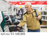senor man pensioner buying Upright Vacuum Cleaner in showroom of electrical appliance store. Стоковое фото, фотограф Татьяна Яцевич / Фотобанк Лори