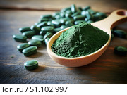 Chlorella or spirulina tablets and powder in spoon on wooden background Nutritional supplement, Detox superfood. Стоковое AI-изображение, AI-художник Елена Гоосен / Фотобанк Лори