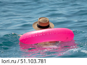 Swimmer, Floating, Ocean: Person relaxing with bright pink inflatable ring and straw hat in calm blue sea on summer day. Стоковое фото, фотограф svetograph / Фотобанк Лори