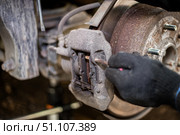 A mechanic removes the retaining elements of a brake caliper while replacing brake pads on a car. Стоковое фото, фотограф Коханова Наталья / Фотобанк Лори