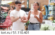 Cheerful interested young man and woman talking friendly while looking for functional furniture and accessories in modern garden store. Стоковое видео, видеограф Яков Филимонов / Фотобанк Лори