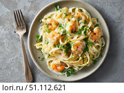 Shrimp Scampi. Spaghetti with shrimp and Creamy Garlic White Wine Sauce on a plate, top view. Scrumptious shrimp and fettuccine pasta with a cilantro, copy space. Linguine Alfredo. Italian cuisine. Стоковое AI-изображение, AI-художник Марина Демидюк / Фотобанк Лори