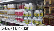 Shelves in a Thai store with biologically active supplements and herbal preparations. In the foreground are white plastic jars with Thai capsules made from natural herbs and plants. The packages vary in color: pink with an inscription in Thai, white and gold, and white and green with a yellow label depicting medicinal plants. On the right in the frame are brown-gold boxes with the inscription Lingzhi Extract - this is an extract of the lingzhi mushroom (reishi), known for its strengthening and general health properties. On the shelves you can see price tags with information in Russian, which indicates the popularity of the products among tourists.The image is suitable for illustrating topics related to natural medicine, Thai drugs, vitamins, mushroom extracts and plant components, a healthy lifestyle and alternative medicine. (2018 год). Редакционное фото, фотограф Анна Кривицкая / Фотобанк Лори