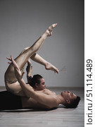 Acrobatic couple perform number on a white background. A duet of gymnasts rehearsing a performance with support. A man and a very flexible woman are dancing. Стоковое фото, фотограф Михаил Решетников / Фотобанк Лори