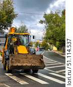 A yellow and black construction vehicle is driving down a street. Russia. Moscow. 19.08.25. Редакционное фото, фотограф Ярославский Максим / Фотобанк Лори