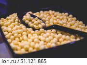 Black spoon scooping up round, puffed corn breakfast cereal from a sleek black container, creating an inviting scene perfect for enjoying a nutritious breakfast or satisfying snack. Стоковое фото, фотограф Ольга Ильина / Фотобанк Лори
