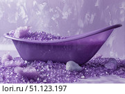 Purple bathtub filled with amethyst bath salts crystals on violet textured background. Стоковое AI-изображение, AI-художник Иван Рябоконь / Фотобанк Лори