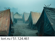 Makeshift tent camp housing displaced people in foggy conditions. Стоковое AI-изображение, AI-художник Иван Рябоконь / Фотобанк Лори