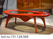 Modern red coffee table with glass top in showroom setting. Стоковое AI-изображение, AI-художник Иван Рябоконь / Фотобанк Лори