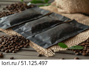 Vacuum sealed coffee beans laying on burlap on wooden table. Стоковое AI-изображение, AI-художник Иван Рябоконь / Фотобанк Лори